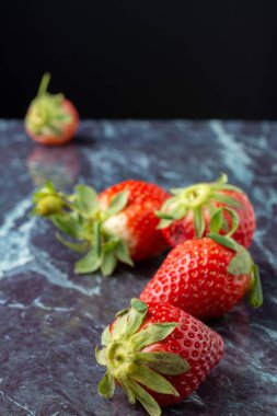 Mavi mermer üzerinde çileklerin üst görünümü, seçici odak, siyah arkaplan, dikey olarak, kopyalama alanı ile