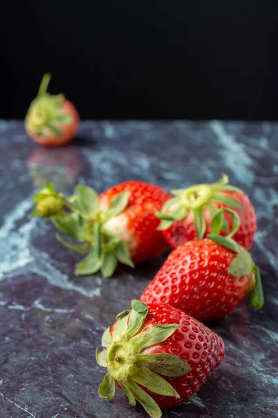 Mavi mermer üzerinde çileklerin üst görünümü, seçici odak, siyah arkaplan, dikey olarak, kopyalama alanı ile