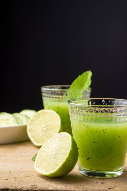 Salatalık suyu, misket limonu, nane ve salatalık dilimleri, seçici odak ile, tahta masa, siyah arkaplan, dikey, fotokopi alanı ile