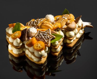 Yılbaşı pastası Noel ağacı şeklinde kumkatlı, çikolatalı. Siyah bardakta krema ve zencefilli kurabiye.