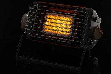 Portatif gaz seramik ısıtıcısı, çalışır ve siyah üzerinde durur.