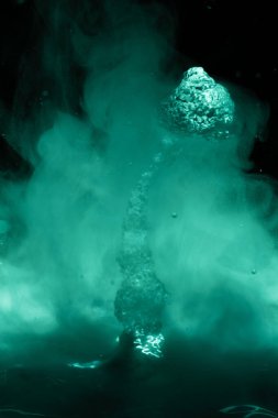 Yeşil sisli uzay gayzerleri ve kara yıldızlı gökyüzünde bir osteroid.