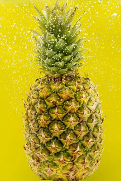 Pineapple under water with bubbles and bubbles on a yellow background — Stock Photo, Image