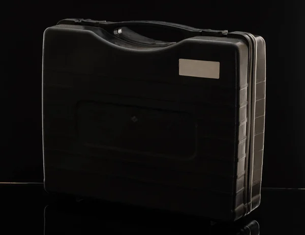 Černý plastový kufr s rukojetí a dvěma západkami na černém — Stock fotografie