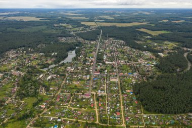 Gökgürültüsü bulutlarının üzerindeki bulutlu bir yaz gününde çam ormanlarında bir köyün uçuşu.
