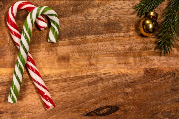 スプルースの枝とクリスマスのおもちゃを持つ木製のトレイ上のクリスマスキャンディーキャラメル杖 — ストック写真