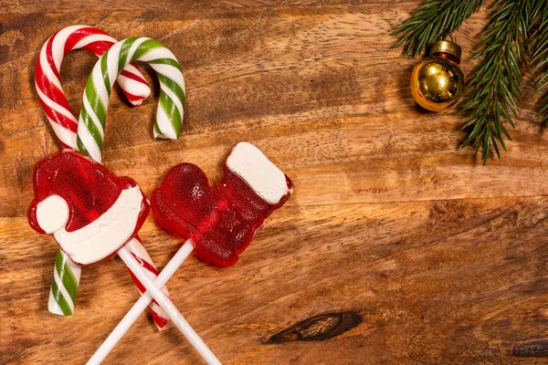 Christmas candy caramel cane on a wooden tray with a spruce branch and a Christmas toy — Stock Photo, Image