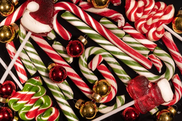 Bonbons de Noël et cannes de caramel avec jouets de Noël sur une table en verre noir — Photo