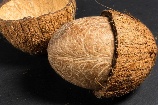 Coco picado em duas metades com toda uma porca macia interna jaz em uma pedra preta — Fotografia de Stock