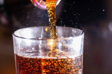 soda cola is poured into a transparent glass close-up, frozen movement