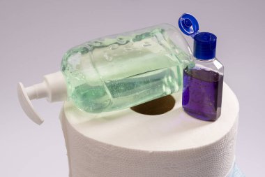 Büyük bir rulo tuvalet kağıdı ya da kağıt havlu antibakteriyel sabun ve beyaz arka planda tıbbi maskeli el antiseptiği.