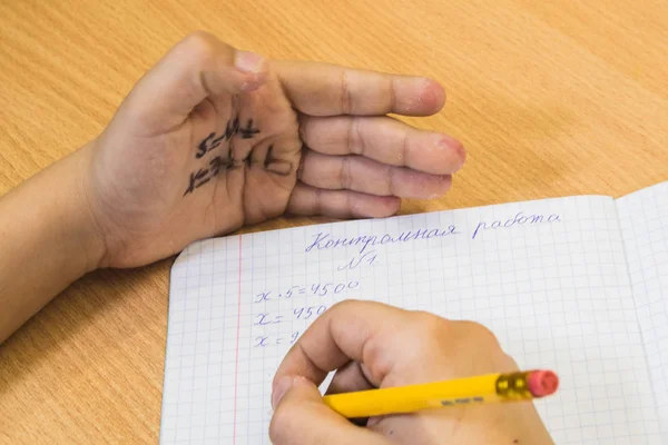 Öğrenci eline yazılmış kopya kağıdından testi siliyor. 