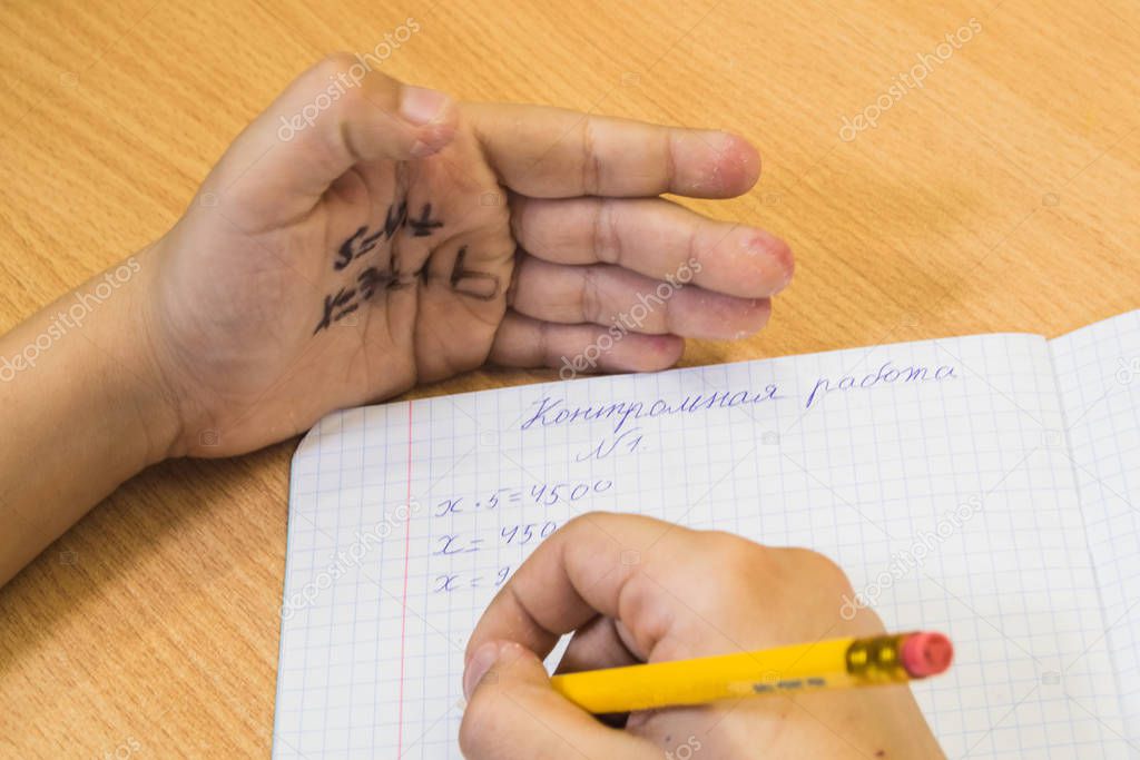 Student writes off the test from the cheat sheet written on the hand. Inscription on a sheet 