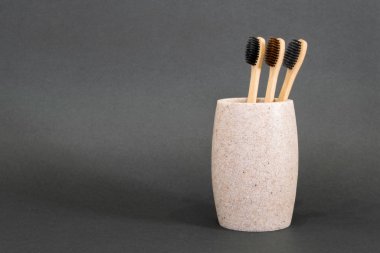 Bambu eko diş fırçaları gri arka planda bir bardakta