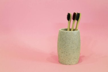 Pembe arka planda bir bardakta eko diş fırçaları