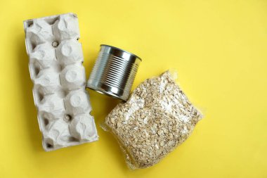 Yiyecek: yumurta, konserve yiyecek ve yulaf homurdanmaları sarı arka planda, boşluğu kopyala