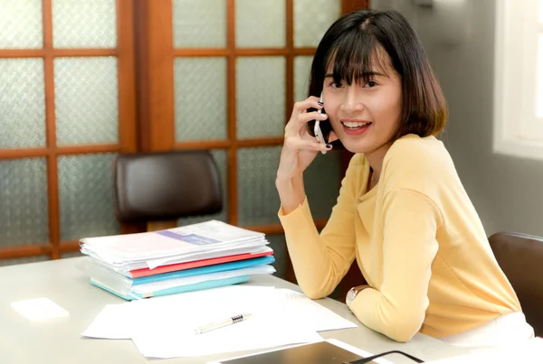 Mutlu genç kadın bir ph cevap ve çalışma masasında oturuyordu