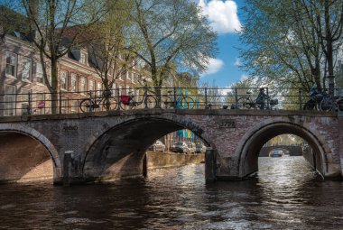 Amsterdam, Hollanda - 15 Nisan 2015: Amsterdam 'da kimliği belirsiz insanların bulunduğu tipik kanal manzarası. Amsterdam Hollanda 'nın başkenti ve en kalabalık şehridir.