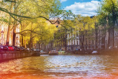 Amsterdam, Hollanda - 15 Nisan 2015: Amsterdam 'da kimliği belirsiz insanların bulunduğu tipik kanal manzarası. Amsterdam Hollanda 'nın başkenti ve en kalabalık şehridir.