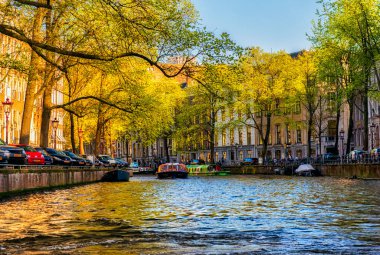 Amsterdam, Hollanda - 15 Nisan 2015: Amsterdam 'da kimliği belirsiz insanların bulunduğu tipik kanal manzarası. Amsterdam Hollanda 'nın başkenti ve en kalabalık şehridir.