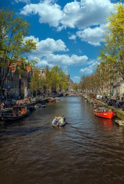 Amsterdam, Hollanda - 15 Nisan 2015: Amsterdam 'da kimliği belirsiz insanların bulunduğu tipik kanal manzarası. Amsterdam Hollanda 'nın başkenti ve en kalabalık şehridir.