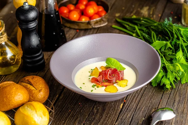 Rustic wooden background, top and side, on a plate, white cream soup of smoked potato, with beef jerky, herbs and vegetables — Stock Image Rustic Wooden Background Top Side Plate White Cream Soup Smoked Stock Image