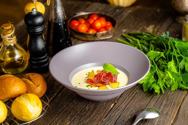 Rustic wooden background, top and side, on a plate, white cream soup of smoked potato, with beef jerky, herbs and vegetables — Stock Image Rustic Wooden Background Top Side Plate White Cream Soup Smoked Royalty Free Stock Photos