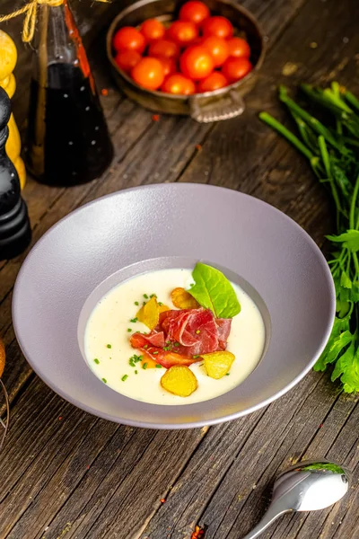 Rustic wooden background, top and side, on a plate, white cream soup of smoked potato, with beef jerky, herbs and vegetables — Stock Image Rustic Wooden Background Top Side Plate White Cream Soup Smoked Stock Photo