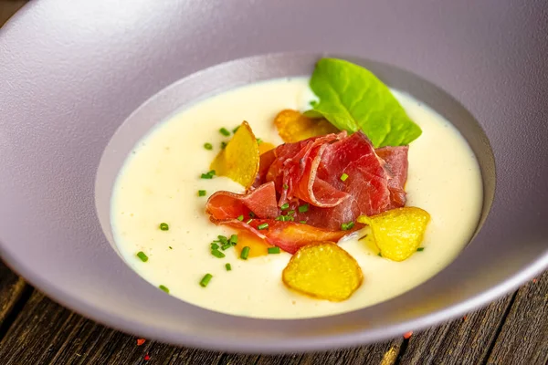 Rustic wooden background, top and side, on a plate, white cream soup of smoked potato, with beef jerky, herbs and vegetables — Stock Image Rustic Wooden Background Top Side Plate White Cream Soup Smoked Royalty Free Stock Images
