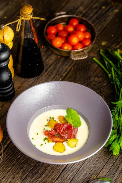 Rustic wooden background, top and side, on a plate, white cream soup of smoked potato, with beef jerky, herbs and vegetables — Stock Image Rustic Wooden Background Top Side Plate White Cream Soup Smoked Royalty Free Stock Images