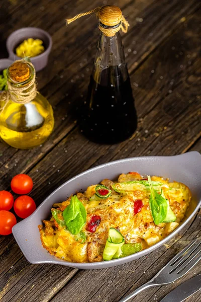 rustic wooden background, top and side, on a plate, roast meat dish, yellow, with vegetables, herbs, fork and knife