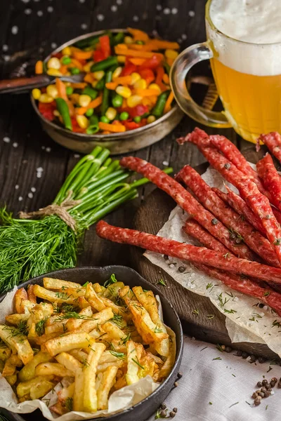 snacks with beer a glass of meat, french fries and salad, on a wooden rustic table or background, fresh herbs