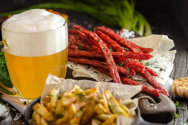 snacks with beer a glass of meat, french fries and salad, on a wooden rustic table or background, fresh herbs