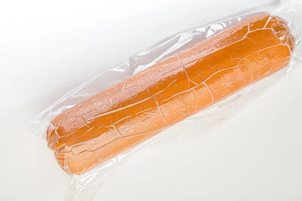 whole cooked sausage, in packaging, lies on an isolated white background