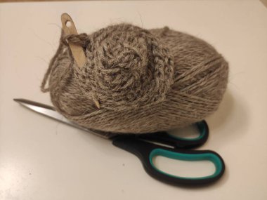 Bir ahşap örgü iğnesi makasın üzerinde duran doğal yün bir kepek içinde açılır. Geleneksel İskandinav örgü aletleri.