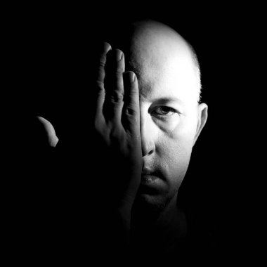 Kel adam yüzünü siyah beyaz bir palmiyeyle kaplıyor.