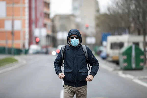 Concept, diseases, viruses, allergies, air pollution. Portrait of young man wearing a protective mask, walking in the city.The image face of a young man wearing a mask to prevent germs, toxic fumes, and dust. Prevention of bacterial infection Corona