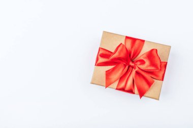 Beyaz arka planda kırmızı fiyonklu karton hediye kutusu.