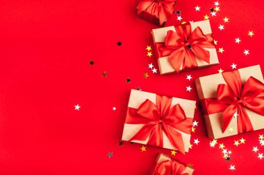 Kırmızı arka planda fiyonklu birkaç hediye kutusu..