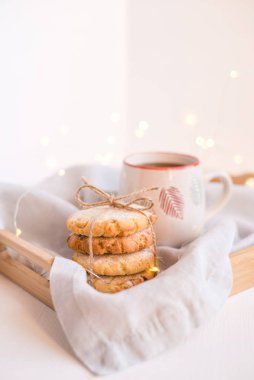 Fresh cookies and cup of tea on a wooden tray.