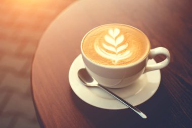 Ahşap masada bir fincan kapuçino..