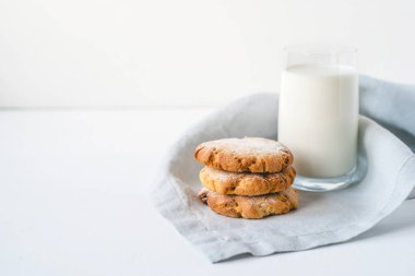 Keten bir peçete ve bir bardak süte istiflenmiş kurabiyeler..