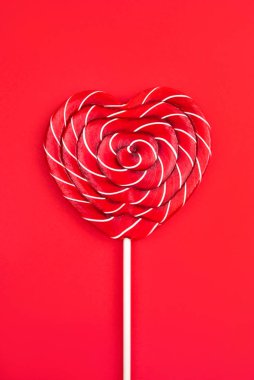 Kırmızı arka planda kalp şeklinde bir lolipop. Sevgililer Günü konsepti.