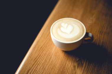 Ahşap masada bir fincan kapuçino..