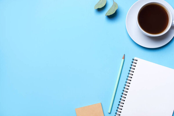 Blue background with notepad, pencil and cup of coffee.