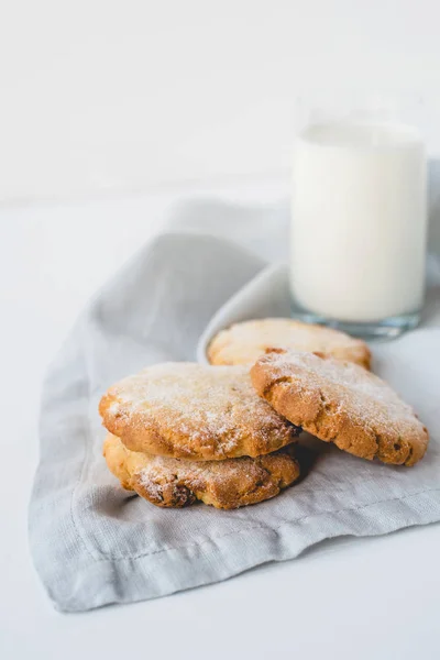 Biscoitos empilhados em um guardanapo de linho e um copo de leite . — Fotografia de Stock