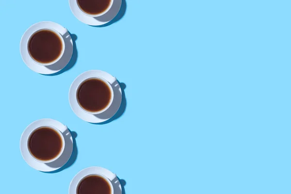 Ramka filiżanek czarnej kawy lub herbaty na niebieskim tle. — Zdjęcie stockowe