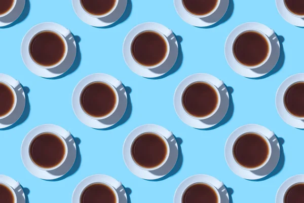 Wzór filiżanek czarnej kawy lub herbaty na niebieskim tle. — Zdjęcie stockowe