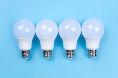 Mavi arka planda dört tane ampul var. Enerji tasarrufu kavramı.