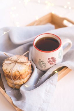 Fresh cookies and cup of tea on a wooden tray.